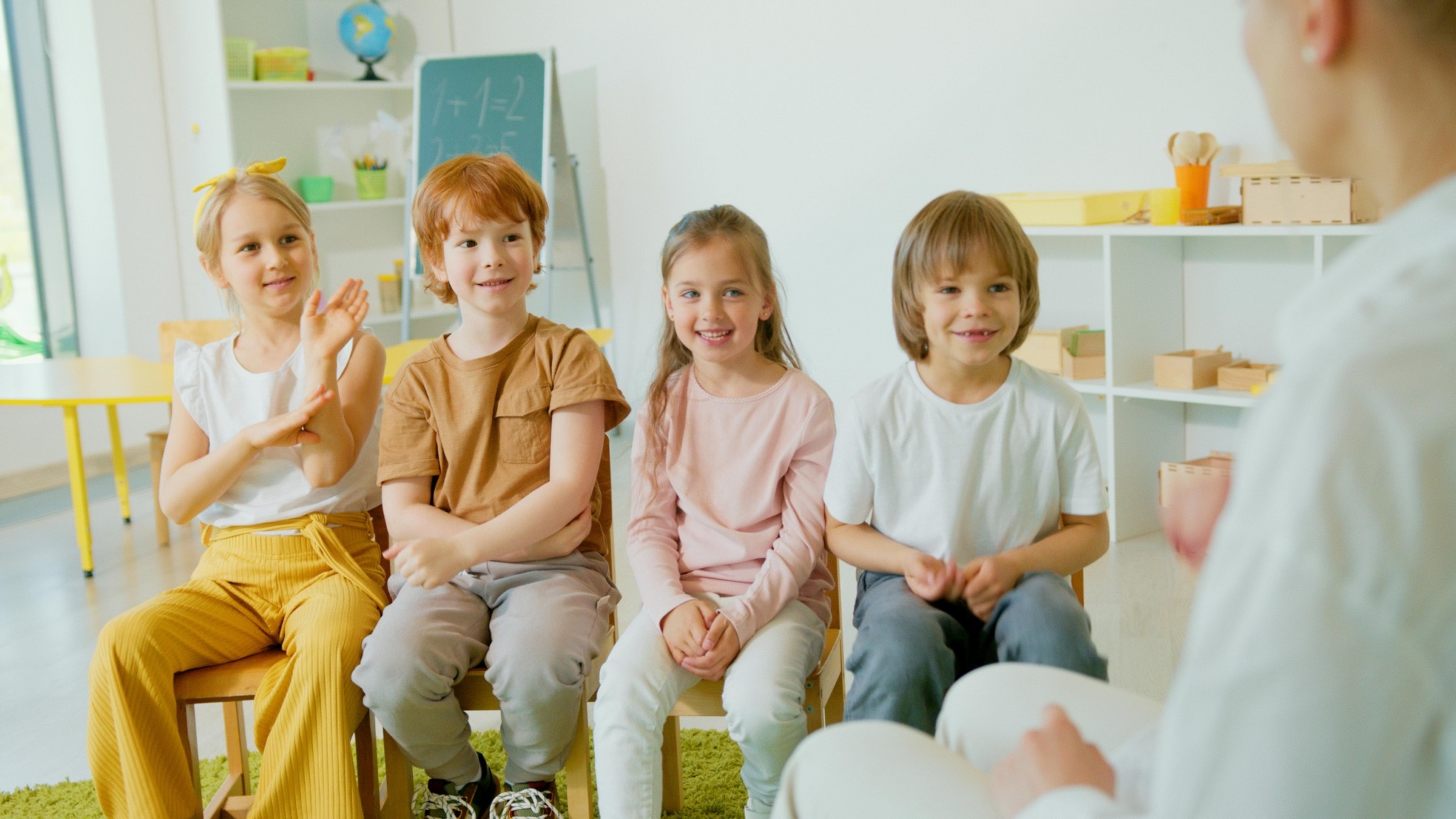 Group of cheerful children clapping hands in a lively classroom setting.